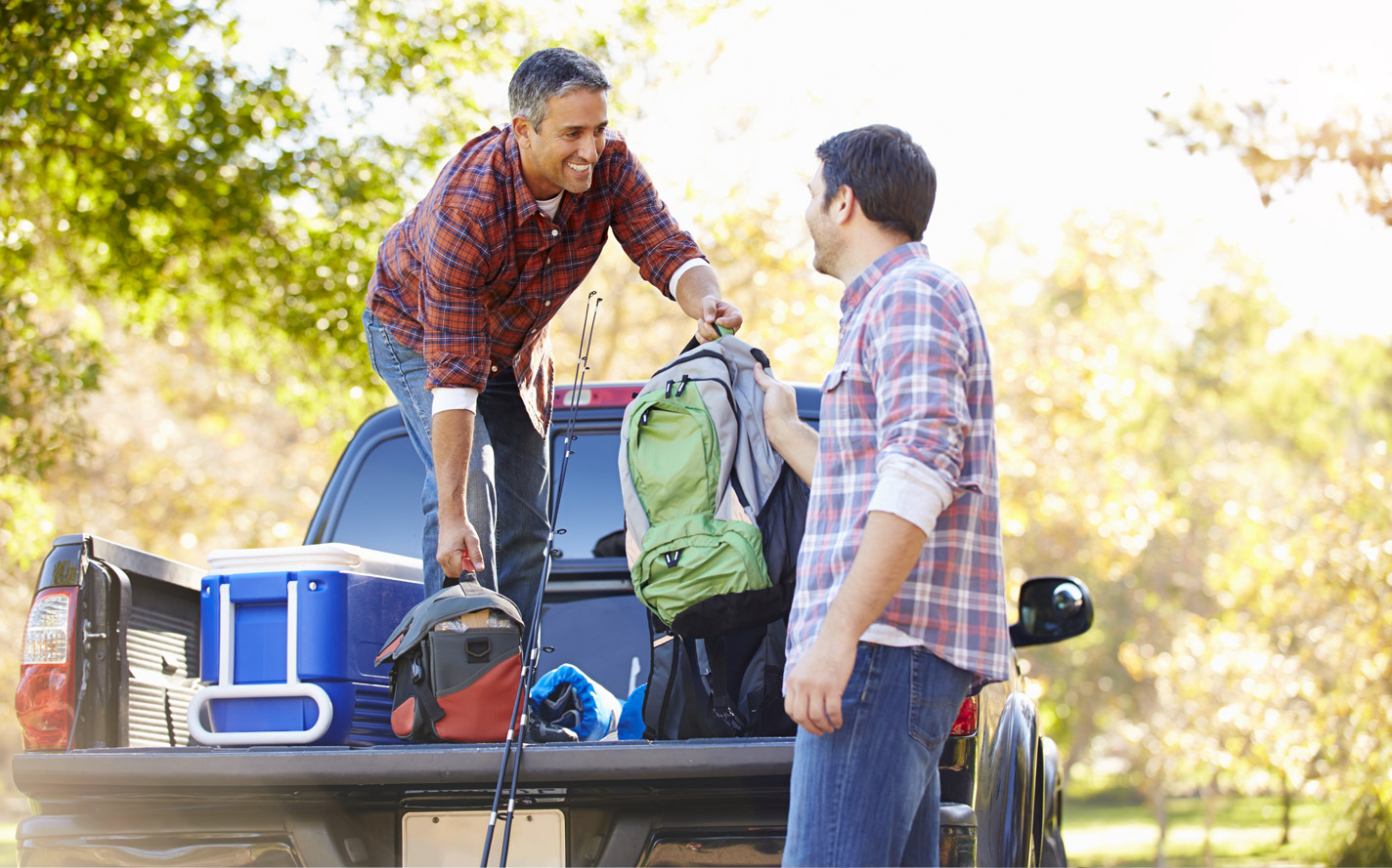 Two guys unloading a truck with fishing gear.