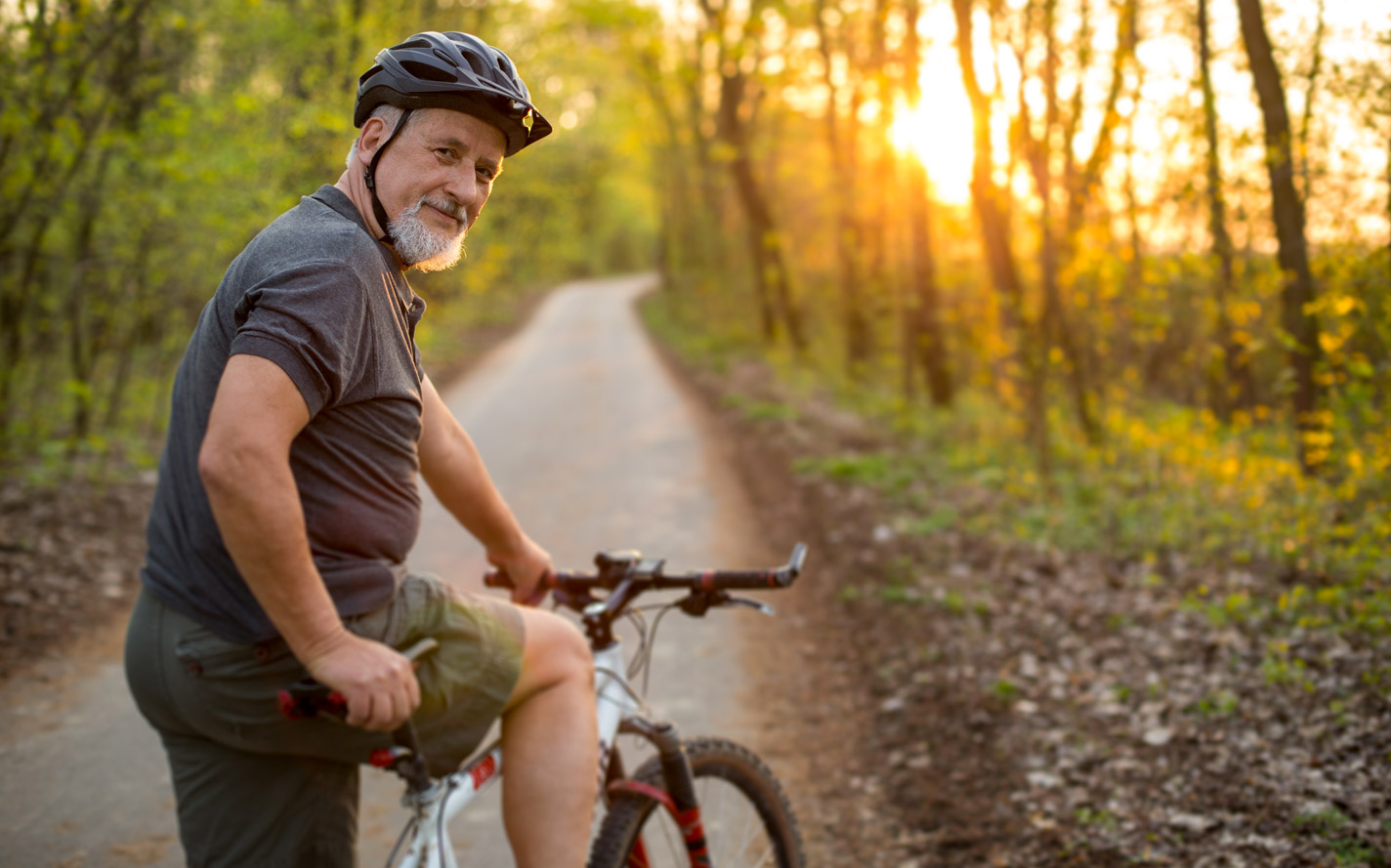 Older man riding a bicycle down the road.